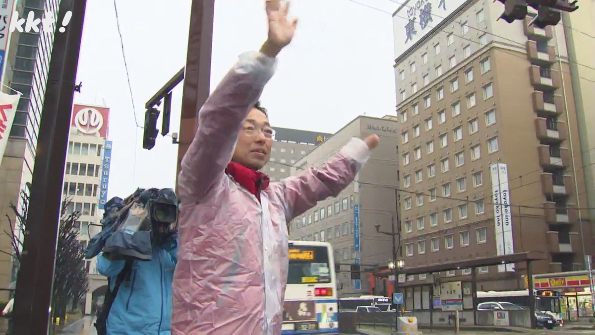 行き交う車に手を振る木村敬氏(25日朝)