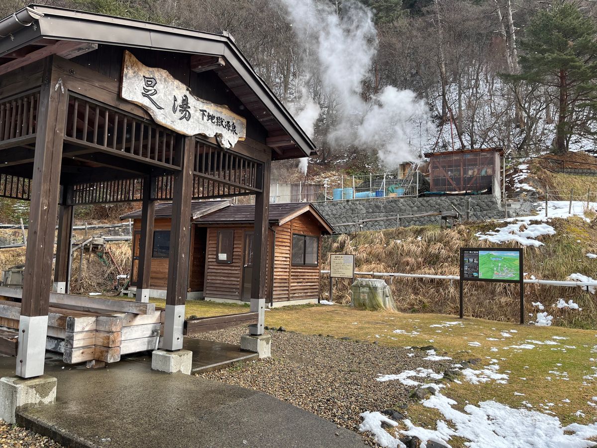 下地獄源泉をバックに立つ案内板