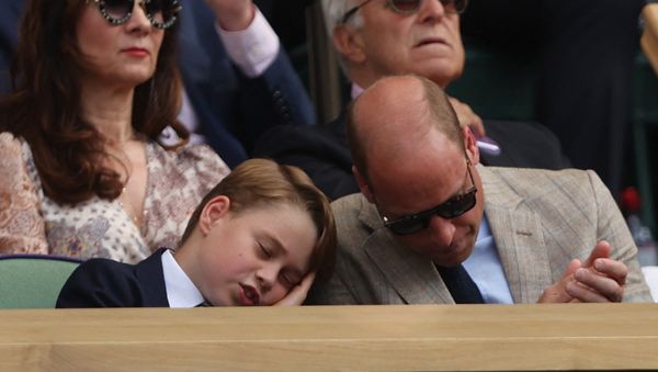 眠くなったのか父にもたれかかるしぐさを見せたジョージ王子(写真:ロイター/アフロ)