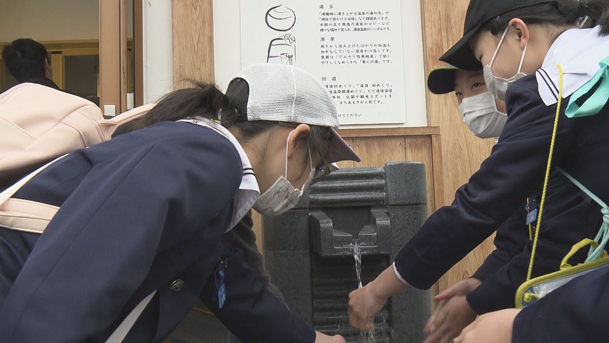 源泉から汲み上げられたばかりの湯に触れる子どもたち