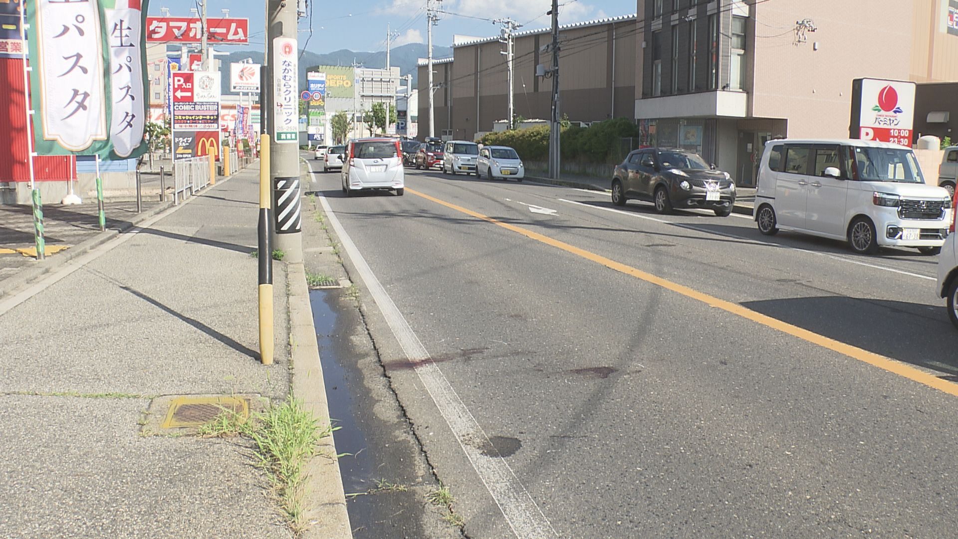 反対車線にある道路脇の縁石に原付バイ…